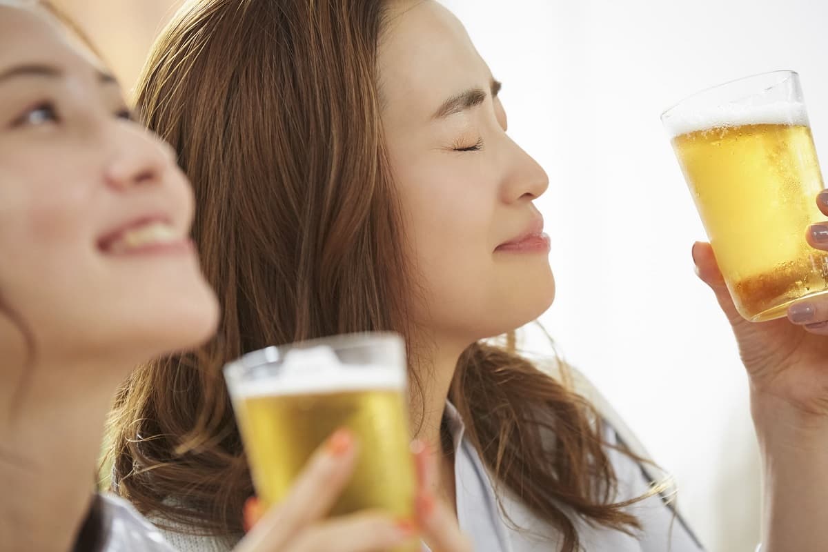ご褒美の馬刺しとビールでお友達とリラックスしている女性のイメージ